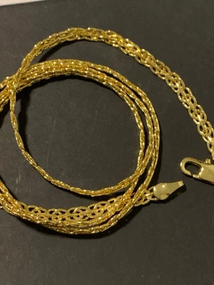 Guldfärgat kedjehalsband - Snyggt guldfärgat halsband med flätad kedja och blank yta. Halsbandet har en klassisk karbinhake och känns både stilrent och trendigt. Perfekt att matcha med andra smycken för en personlig look.