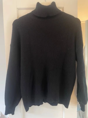 Svart polotröja från BikBok - Säljer en svart ribbstickad polotröja från BikBok. Tröjan har lång ärm, hög polokrage och är gjord i ett mjukt, stretchigt material. Perfekt för lager på lager och enkel att matcha med olika outfits.