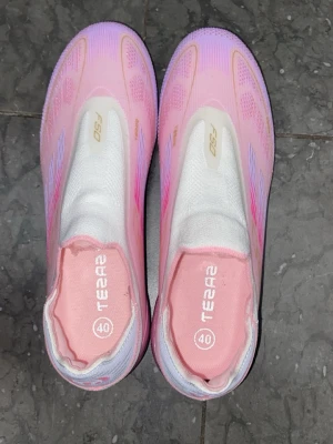 Adidas F50 - Säljer ett par riktigt snygga fotbollsskor i rosa och lila med vita detaljer. Modellen är F50 och skorna har en strömlinjeformad design med elastisk ovandel för bra passform. Perfekta för dig som vill sticka ut på planen!