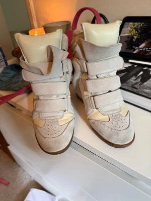 Isabel marants bekett - Kilklack skor (wedge sneakers) i beige mocka och skinn med flera breda kardborreband. Från isabel marant i storlek 38. Bra skick. Kan posta eller mötas i stockholm.