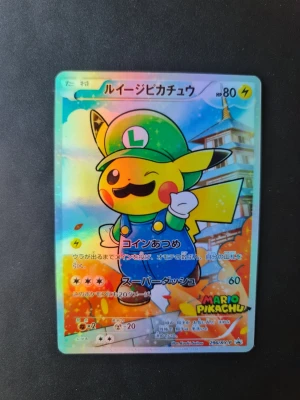 Proxy Pokémonkort Luigi Pikachu Promo  - Unikt proxy Pokémonkort med Pikachu utklädd till Luigi från Mario-serien. Kortet har en holografisk yta och japansk text. Färgerna är klara med grönt, gult och blått i motivet. Perfekt för samlare av Pokémon eller Nintendo-relaterade kort.