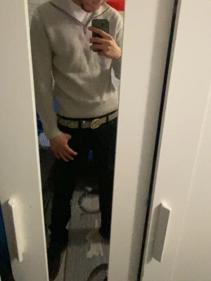 Ljusgrå stickad tröja från Dobber - Säljer en ljusgrå stickad tröja från Dobber med halv dragkedja och hög krage. Tröjan har ribbstickad struktur, långa ärmar och breda muddar vid ärmslut och nederkant. Perfekt för lager på lager och enkel att matcha.