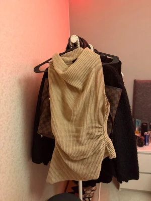 Beige ribbad ärmlös topp med polokrage - Säljer en beige ribbad topp utan ärmar med hög polokrage. Toppen har en figurnära passform och är gjord i ett stretchigt, mjukt material som känns skönt mot huden. Perfekt att styla med jeans eller kjol för en trendig look. Råkade beställa två styckna av samma så vill bli av med den här också, testat på bara intr använt, 