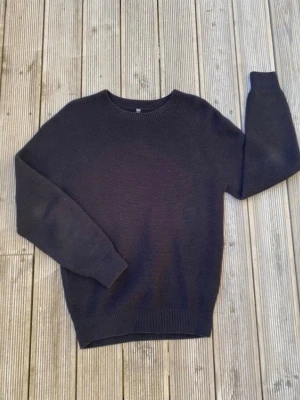 Svart stickad tröja från Uniqlo - En stilren svart stickad tröja från Uniqlo i storlek S. Tröjan har rund halsringning, ribbade muddar vid ärmslut och nederkant samt en klassisk rak passform. Perfekt för lager på lager och enkel att matcha med olika outfits.