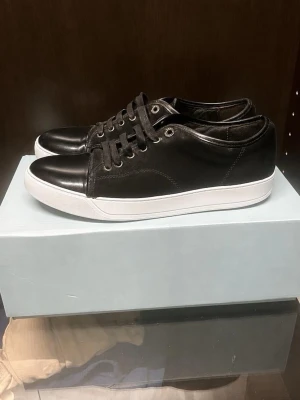Lanvins  - Stilrena lanvins och svarta skosnören. Klassisk låg modell med metallöljetter och diskret sömnad längs sidorna. Passar perfekt till jeans eller chinos för en clean look. Första bilden togs med sulkräm och därför ser vitare ut väldigt enkelt att tvätta dom. Bättre pris vid snabb affär. Storlek 43 