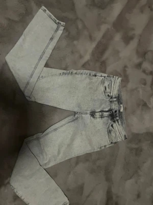 Ljusgrå raka jeans - Snygga ljusgrå jeans med rak passform och klassisk femficksdesign. Jeansen har en hög midja och är tillverkade i denim med en lätt tvättad look. Perfekta för en avslappnad och trendig stil.