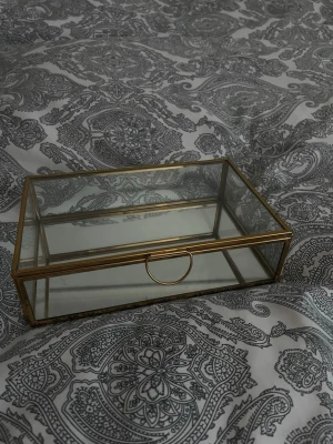 Rektangulär glas smyckesbox - Stilren smyckesbox i glas med guldfärgade mässingsdetaljer. Rektangulär form med transparent lock och sidor, perfekt för att förvara och visa upp dina favoritsmycken. 