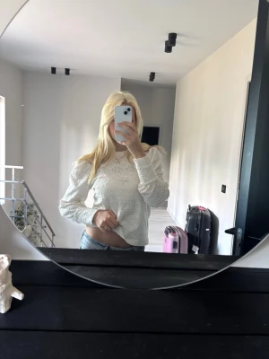 Vit spetsblus med lång ärm - En vit blus med puffiga armar och fina detaljer.