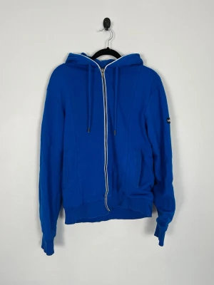 Armani Jeans AJ Zip Hoodie Blå Slim Fit Herr M Full Zip - • Storlek: M • Färg: Klarblå med grått foder och vita detaljer • Passform: Slim Fit  • Krage: Huva • Material: 70% viskos, 27% polyamid & 3% elastan  Skick: Plagget är i väldigt fint skick. Eventuella anmärkningar anges alltid tydligt i beskrivningen och visas på bilderna.  Nypris: Cirka 2 000 kr.  📦 Skickas snabbt och packas omsorgsfullt. 💬 Hör gärna av dig om du har frågor eller vill se fler bilder. 🤝 Samfrakt erbjuds vid köp av flera plagg – kika gärna in mina andra annonser!