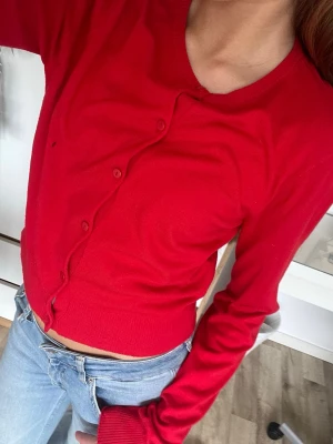 Röd kofta  - Säljer en röd kofta från H&M. Koftan har ett litet hål som man kan se i bilderna. Enkelt att sy ihop jag är bara lat. Koftan andas bra och är mycket bekväm. Använt en gång på julafton. Storlek XS.
