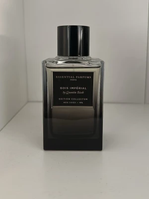 Bois Impérial collector edition  - Snygg parfymflaska från Essential Parfums, Bois Impérial Edition Collector. Flaskan är rektangulär med svart och transparent glas som tonar från ljust upptill till mörkt nedtill. Svart, blank kork och stilren etikett framtill.