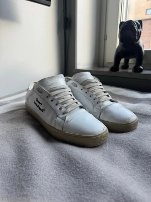 Saint Laurent skor - Snygga vita sneakers från Saint Laurent, skicket är inte det bästa men de funkar fortfarande, de defekter som är på skorn är inget man ser, priset går alltid att diskuteras, inget og eller box följer med!
