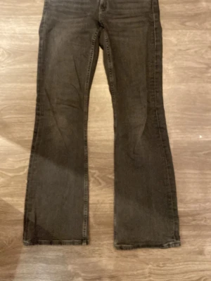 Svarta bootcut jeans - Säljer ett par svarta bootcut jeans från Gina Tricot. Jeansen har klassisk femficksdesign och silvriga knappar. Jeansen har utsvängda ben och är tillverkade i ett mjukt denimtyg som ger en skön passform. 