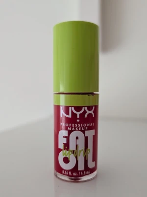 NYX Fat Oil Lip Drip läppglans röd - Använd en gång. NYX Fat Oil Lip Drip är ett läppglans med oljebaserad formula i en djup röd nyans. Förpackningen har en grön kork och transparent flaska som visar färgen. Ger glansig finish och återfuktar läpparna. Perfekt för dig som vill ha ett glossigt resultat.