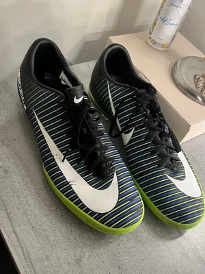Nike fotbollsskor - storlek 45,5 - Säljer ett par Nike fotbollsskor med svart, blå och limegrön färg. Skorna har vita detaljer och stora Nike-loggor på sidorna. Är använda, finns bilder. Vid funderingar skriv, priset kan diskuteras.