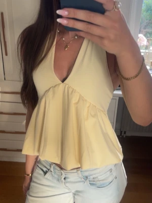 Ljusgul halterneck topp - Snygg ljusgul topp med  volang nedtill o rosettknyt i nacken! Nyskick💗Samma topp i min profilbild 