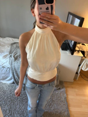 Champagnefärgad halterneck topp - champagnefärgad halterneck topp i glansigt material. Perfekt för dig som vill ha en chic och trendig look.