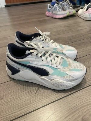 Puma sneakers rs-x - Snygga sneakers från Puma i vitt, ljusblått och marinblått. Tror det är modellen rs-x. Så otroligt bekväma! Smutsiga men går kanske att tvätta bort. Storlek 37,5 men passar mig som har 36 också, så rätt små. 