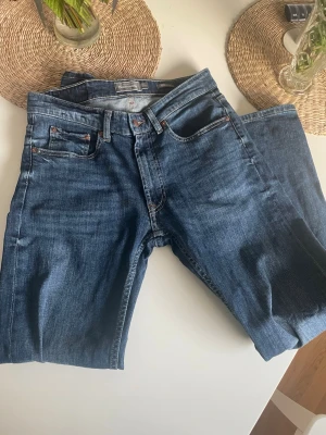 Mörkblå raka jeans - Snygga mörkblå jeans med klassisk rak passform och fem fickor. Jeansen har orange sömmar och silverfärgade nitar. Tillverkade i slitstarkt denimtyg som ger en tidlös look. Perfekta till vardags och lätta att matcha med olika stilar. Dem är använda bara några gånger. Hör av dig vid frågor! Vid snabb affär kan jag gå ner i pris