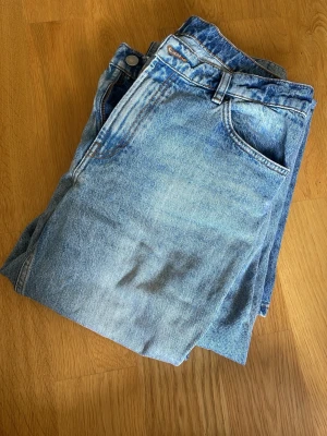Blå raka jeans från Lindex - Ett par klassiska blå jeans från Lindex med rak passform och fem fickor. Jeansen har en ljus tvätt och är gjorda i slitstarkt denimtyg med kontrastsömmar. Perfekta till en avslappnad stil och funkar året runt.