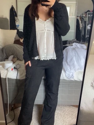 Svart kofta från vila - En svart, mjuk och öppen kofta från Vila. Koftan har långa ärmar och ribbade muddar vid ärmslut och nederkant. Perfekt att slänga över en topp för en avslappnad look. Enkel och stilren design som passar till det mesta.