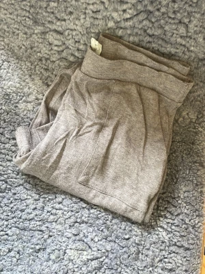 Grå yogabyxor med bred mudd - Säljer ett par grå yogabyxor med bred resår i midjan och stora fickor framtill. Byxorna är i mjukt och stretchigt material, perfekta för chill dagar hemma eller när du vill vara extra bekväm.