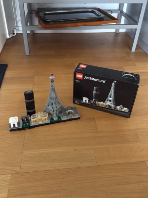 LEGO Architecture Paris 21044 - Byggsats från LEGO Architecture-serien, modell Paris 21044. Innehåller flera ikoniska byggnader som Eiffeltornet och Triumfbågen i olika färger som grått, svart, vitt och guld. Perfekt för dig som gillar arkitektur och samlarprylar. Det saknas två små gröna bitar (se bild). Öppnad och använd.