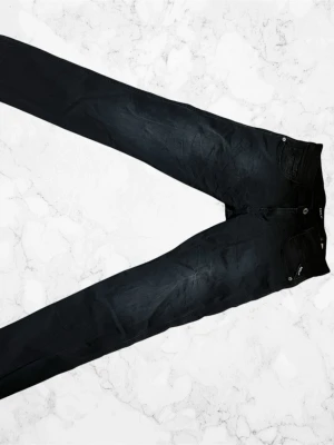 Svarta Replay Jeans Anbas - Snygga svarta skinny jeans och klassisk femficksdesign. Jeansen har smal passform och stretchigt material som sitter tajt längs benen. Perfekta för en trendig och stilren look. Använda 1 gång, så jeansen ser helt nya ut.