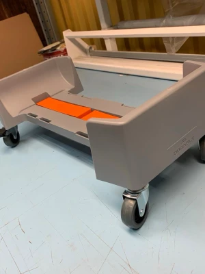 Grå rullvagn för förvaring - Säljer en grå rullvagn från Dolle med fyra hjul och orange detaljer i mitten. Vagnen är tillverkad i plast och metall och har en rektangulär form med höga kanter, perfekt för att flytta eller förvara saker smidigt.