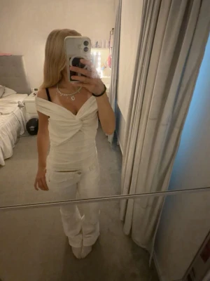 Vit omlott offshoulder topp - Säljer en snygg vit omlott topp med offshoulder-design och twistad detalj framtill. Perfekt när man vill känna sig lite extra fin