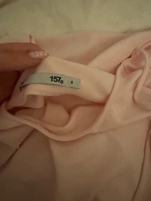 Ljusrosa omlottklänning med snörning - Söt ljusrosa omlottklänning med snörning i midjan och långa ärmar. Klänningen har en mjuk känsla och är perfekt för dig som gillar en feminin och enkel stil. Passar dig som vill ha något bekvämt men ändå snyggt.