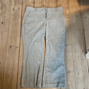 Grå linnebyxor från Five Units - Snygga grå linnebyxor från Five Units med klassisk rak passform och diskreta fickor fram och bak. Byxorna har bälteshällor och stängs med knapp och dragkedja. Perfekta för en chill och stilren look.