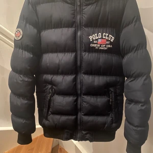 Mörkblå pufferjacka Polo Club från Team Sportia (Vinter jacka) - ✨Superfin vinterjacka – i nyskick! ✨ Säljer min sons vinterjacka som tyvärr nästan aldrig blev använd – Han har använt den en kort period under en säsong Kvaliteten är riktigt bra (nästan som ny)  och jackan är i perfekt skick, utan några tecken på slitage. Den är varm, bekväm och perfekt nu till vintern ❄️ Passar utmärkt för den som söker en snygg och rejäl vinterjacka till ett riktigt bra pris!  Hör gärna av dig om du vill veta mer, se fler bilder eller diskutera pris.
