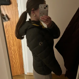 Svart pufferjacka med gul huva från WÅVEN - Säljer en svart pufferjacka från colmar med gul insida. Perfekt för kalla dagar och har en riktigt snygg kontrast med den gula detaljen. Den har några skavanker på ärmen och i fickan därav går pris att diskuteras!💕