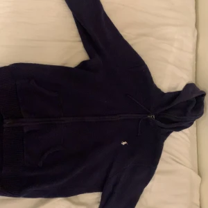 Mörkblå hoodie från Polo Ralph Lauren - Säljer en mörkblå hoodie från Polo Ralph Lauren med dragkedja och huva. Tröjan är kaschmir och står L i storlek fast det passar S/XS