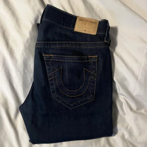 True religion jeans - Snygga jeans med true religion loggan på fickorna i en mörkblp färg. Storlek 32, relaxed fit.