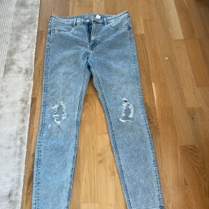Curvy ljusblå ripped jeggings &Denim - Säljer ett par ljusblå curvy jeggings från &Denim i storlek 44. De har hög midja, ankellängd och slitna detaljer vid knäna för en cool look. Materialet är stretchigt jeans och passformen är tight. Perfekta för dig som gillar trendiga och bekväma jeans.