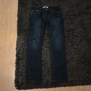 Levi's 512 Slim Taper jeans mörkblå - Mörkblå Levi's 512 Slim Taper jeans med klassisk femficksdesign och snygga kontrastsömmar. Jeansen har en smal passform som smalnar av nedtill och är tillverkade i slitstarkt denimtyg. Perfekta för en stilren och modern look.