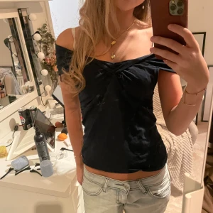  offshoulder topp - Säljer en mörkblå offshoulder topp med snygg snörning framtill. Toppen är croppad och har en tight passform som framhäver figuren. Materialet känns mjukt och stretchigt, perfekt för dig som gillar en stilren och trendig look.