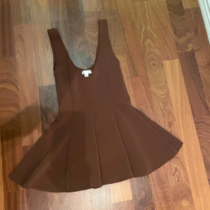 Brun ärmlös klänning från H&M - Säljer en brun ärmlös topp från H&M i storlek S. Toppen  har en snygg utsvängd form med djup rundad ringning och markerade sömmar.  Har aldrig använt den 💕
