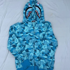 Ljusblå bape kofta - En ljusblå bape kofta med eld design runt om hela och dubbel dragkedja, använd 3-4 gånger under sommaren sen aldrig mer. Fraktas samma dag! Hör gärna av er med frågor eller om ni är intresserade! (M/S)