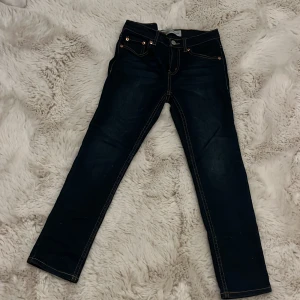 Levi's 512 Slim Taper jeans mörkblå - Snygga Levi's 512 Slim Taper jeans i mörkblå tvätt med klassiska kontrastsömmar och fem fickor. Modellen har smal passform med avsmalnande ben och normal midja. Ikonisk Levi's patch baktill och röd logotagg på bakfickan. Perfekt för en cool och stilren look.