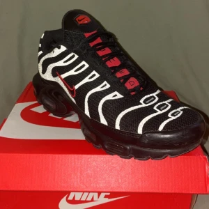 Nike Air Max Plus Zebra Svart/Vit/Röd - Nike Air Max Plus sneakers med svart mesh-överdel, vita zebraränder och röda detaljer. Snygg röd Swoosh på sidan och AIR-text på plösen. Platt sula meds synliga luftkuddar och robust yttersula. Perfekt för dig som gillar djärv stil och streetwear.