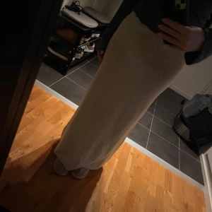 Ljusbeige stickad långkjol - Mysig och enkel ljusbeige långkjol i stickat material. Kjolen har en rak passform och bred resår i midjan för extra komfort. Perfekt för dig som gillar en avslappnad och stilren look.