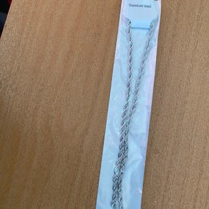 Rostfritt stål halsband (unisex)  - Snyggt halsband i silverfärgat rostfritt stål med tvinnad kedja. Perfekt för dig som gillar stilrena och moderna accessoarer. Låset är enkelt att använda och kedjan har en cool, vriden design som ger extra edge till din look. 60cm långt.