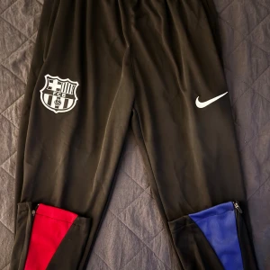 Svart Nike FC Barcelona Tracksuit - Svart Barcelona fotbollsbyxor med blått och rött, sponsrade av nike och spotify, kom dm för frågor och mer bilder ! Passar S, kom dm för frågor och mer bilder !