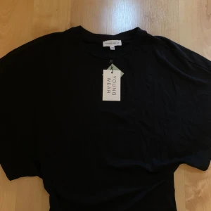 Svart topp från Young Wear - Svart t shirt som är tightare i midjan och har lite vida armar skulle säga att den passar om du brukar ha xxs/xs i tröjor 💗Prislappen är på och aldrig använd