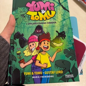 Yumi & Tomu: I Spelmästarens händer - Följ med Yumi och Tomu på ett spännande äventyr fyllt av humor, mystik och farliga växter! Perfekt för unga läsare som gillar tecknade berättelser och action. Färgstarka illustrationer och roliga karaktärer gör boken extra underhållande.