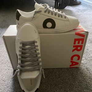 Oliver Cabell (HELT NYA!!) storlek 40/41 - Supersnygga vita sneakers från Oliver Cabell i modellen Low 1 med grå/svart logga på sidan. Storlek: 40, (funkar möjligtvis till 41 eller där emellan också) Skick: Helt NYA, aldrig använda (endast provade – för små för mig). Levereras i originalkartong. Självklart ÄKTA 
