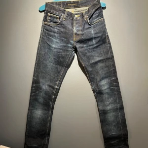 Nudie Grim Tim US Dry Selvedge - Nudie jeans Grim Tim - us selvage / selvedge 14,75 oz Denim tillverkad av anrika, numera nedlagda White Oak Cone Denim i USA W28, L32, har dock varit uppvikta, se bilder något slitna i grenen. Bland de fetaste Nudie jeansen money can buy och går inte att köpa nya längre!